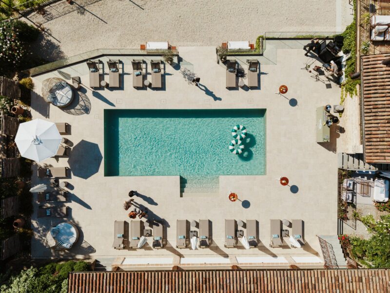 The garden and pool terrace of La Villa Hotel in Piedmont on a warm afternoon, with sun loungers, potted plants and vineyard views, a calm and private setting